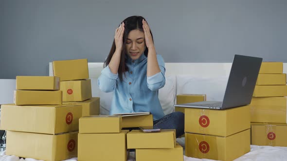 stressed woman using laptop computer and working problem to selling product online on a bed at home