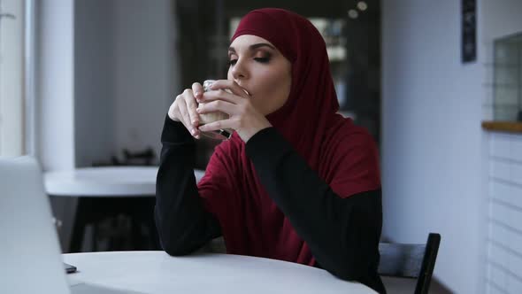Attractive Female with Unbelievably Beautiful Eyes and Hijab is Drinking Cappuccino alt