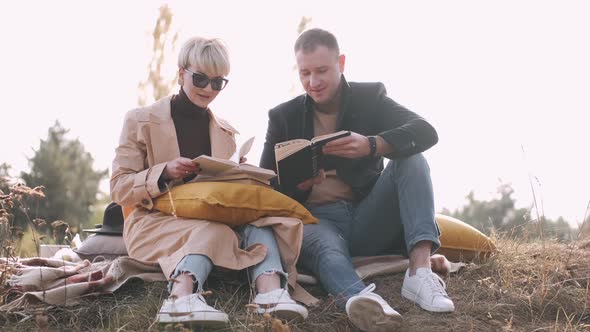 Couple Sitting and Reading Fiction Books Outside in Forest