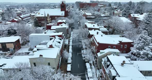 American town during winter snow aerial in evenign. Pretty trees covered in snowfall. Aerial reveal