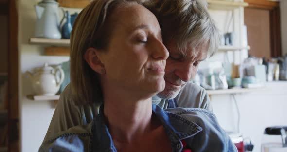 Senior caucasian couple wearing aprons and embracing before cooking in kitchen