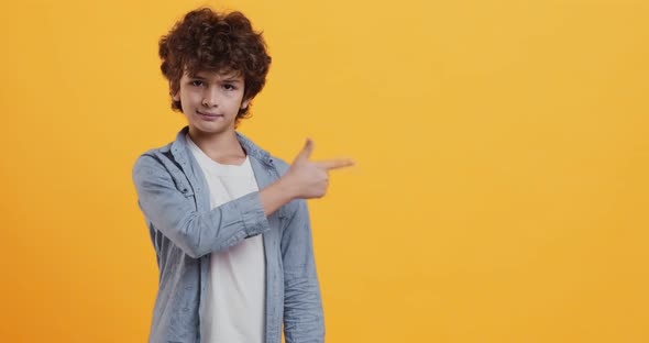 Great Promo. Emotional Boy Gesturing Aside, Showing Copy Space Over Orange Background