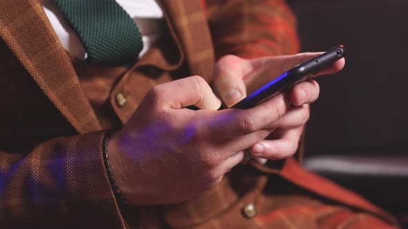 Man in a Brown Suit is Holding a Mobile Phone a Smartphone