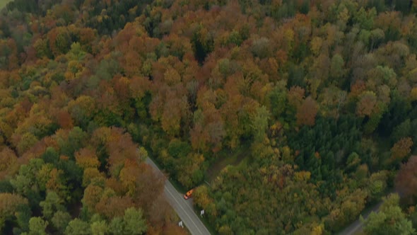 Look down panning shot from a monastery next to a forest in autumn down to a green meadow