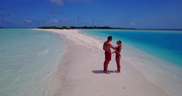 Happy man and woman on honeymoon vacation have fun on beach on clean white sand 4K background