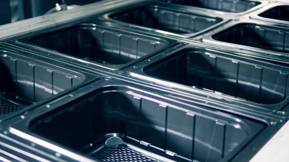 Closeup of Black Plastic Containers Molding Process