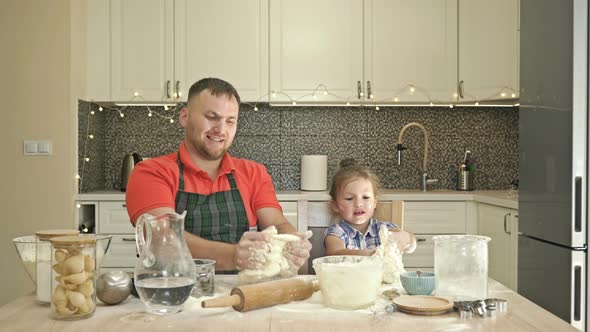 Surprise for Mom. Dad and Daughter, 5-6 Years Old, Are Kneading Dough in the Kitchen. It Looks Like