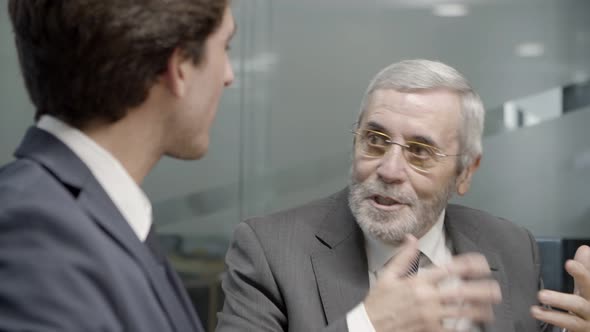 Mature Businessman Talking To Younger Colleague