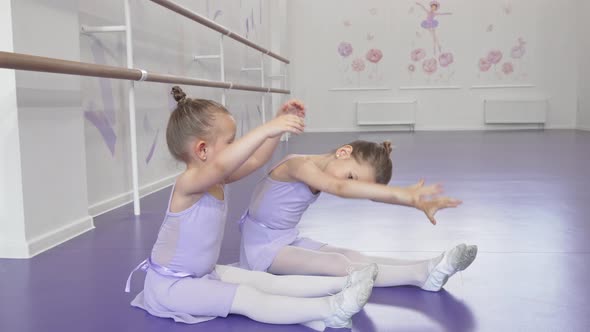 Cute Little Ballerinas Stretching Together at Dancing School Together