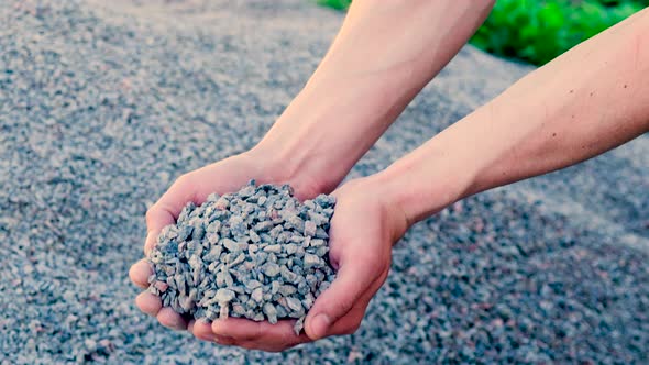 A Man Holds Small Rubble in His Hands