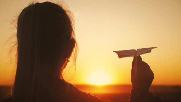 Happy Little Girl Playing with a Paper Airplane Outdoors During Sunset. Concept Big Child Dream