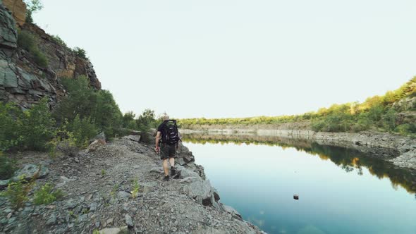 tourist with a backpack on his back is going along the bank of the lake