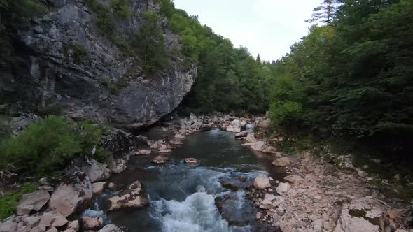 FPV Aerial Shot Dynamic Flying at Natural Landscape River Canyon in the Dense Green Forest and Rapid