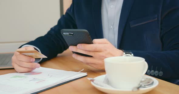 A Businessman Is Sitting at a Table in a Cafe and Working