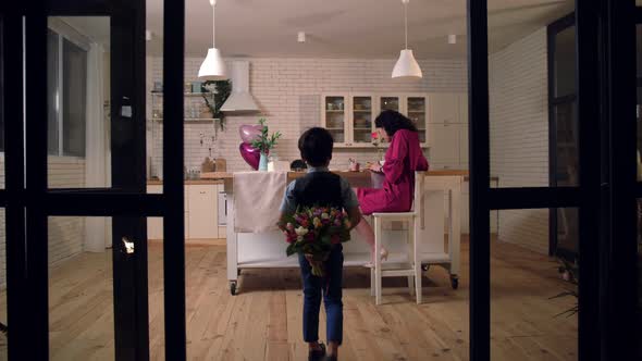 Son Surprising Mother with Flowers in Kitchen