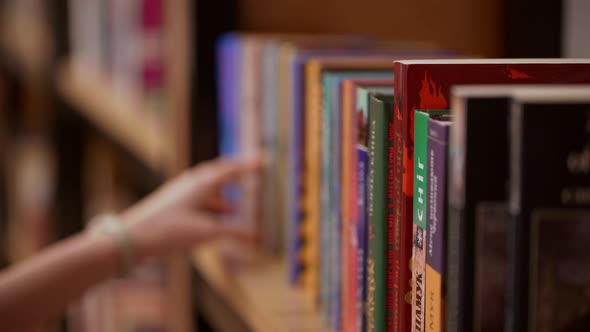 Close Up Footage of Female's Hand Choosing Book From Shelf in Library