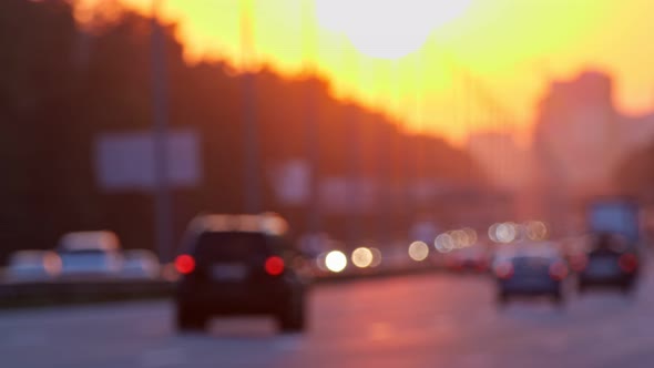 Blurred City Traffic on Highway at Sunset. Lights of Passing Cars Against the Setting Sun. Rush Hour