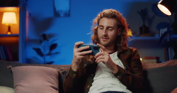 Young Hipster Man Rotating Smartphone Screen To Landscape Horizontal Mode and Sitting Comfortable
