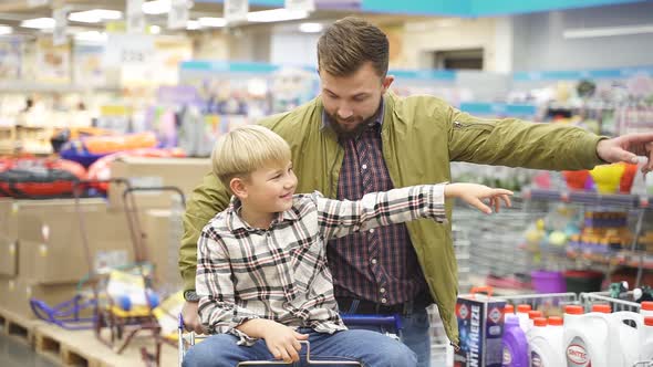 Positive Child Boy Enjoys Shopping Time with Father in Supermarket