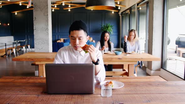 Businessman using laptop in cafeteria at office 4k