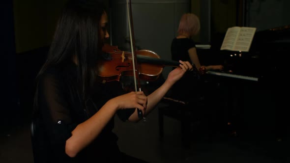 Two women playing a violin and piano