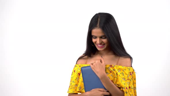 Happy Indian girl holding a notebook and smiling