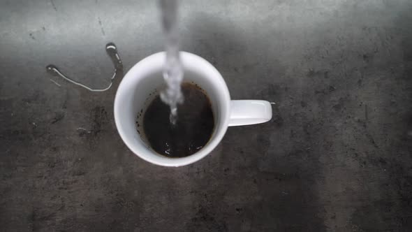 Pouring Hot Water in Slow Motion on Grounded Coffee Crystals in a White Ceramic Cup and Brewing