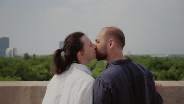 Young Couple Admiring Urban Landscape From Building Roof