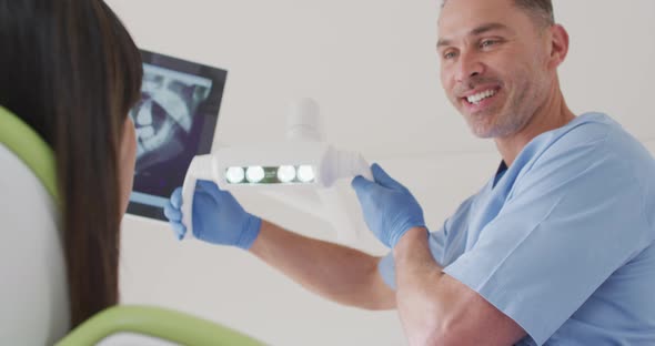 Smiling caucasian male dentist preparing female patient at modern dental clinic