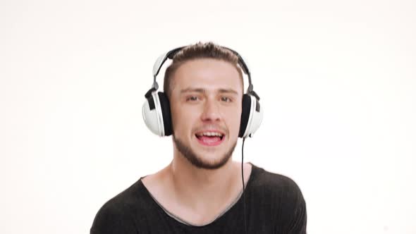 Portrait of Young Handsome Man Listening Music in Headphones and Dancing