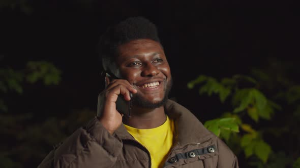 Friendly Black Hipster Chatting on Phone at Night