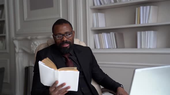 African-American Bearded Man in a Black Suit, Shirt, Stylish Glasses. A Businessman Is Working on a