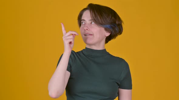 Young girl thinking about something standing isolated on yellow studio background