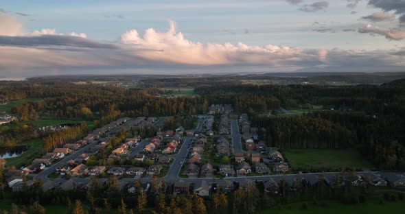 Wide establishing shot of an American developed neighborhood surrounded by forests and cloudy skies