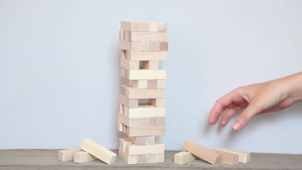 Risks in the business. Wooden brick falls on the table, the tower falls.