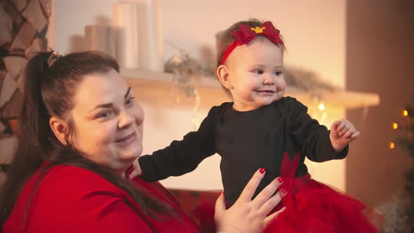 Christmas Concept - A Plump Smiling Woman Holding Her Little Baby Daughter