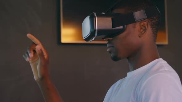 Side view of young black male executive using virtual reality headset at desk in modern office 4k