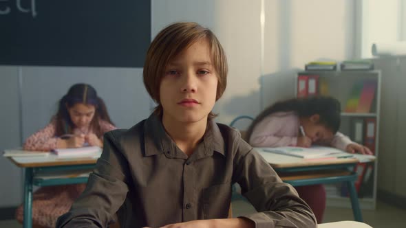 Serious Schoolboy Looking at Camera in Classroom