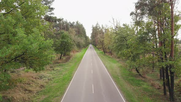 Professional cyclist rides on aero road bike on empty car road. Triathlete is riding on bicycle