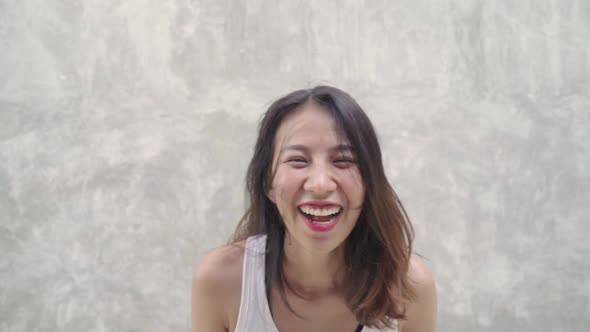 young Asian backpacker blogger woman feeling happy dancing on street while traveling.