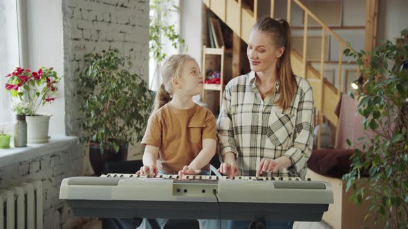 Single Mother and Her Young Daughter Look at Each Other and Smile at Each Other While Playing the