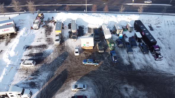 Aerial: Frozen parking lot acting as freedom convoy base camp beside highway at morning in Ottawa, O