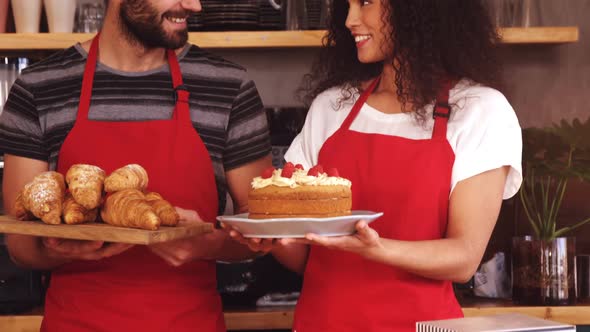 Waiter and waitress holding a tray of croissants and cake