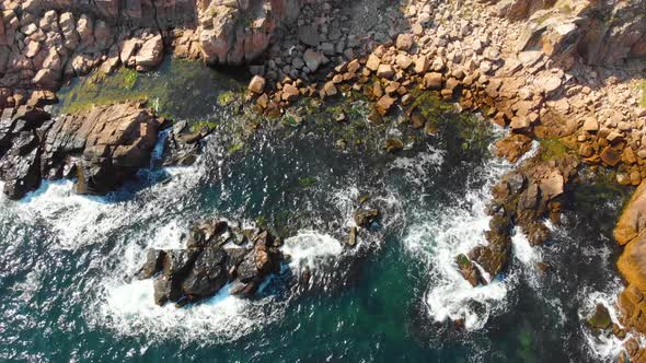 Ascending aerial footage of a waves crashing in a rocky shore.