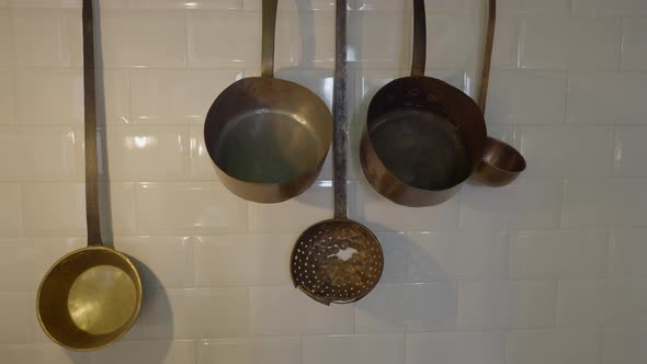 Pushout Shot of Metal Pots Hanging on White Tile Kitchen Wall