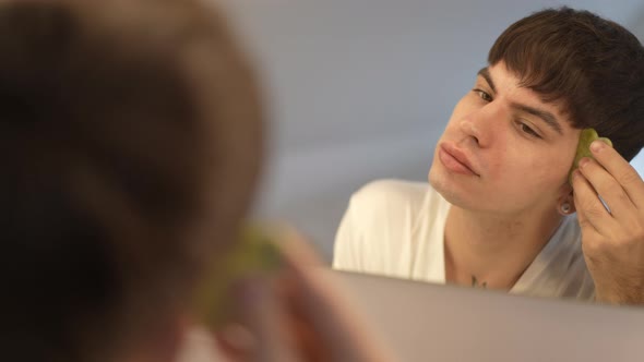 Reflection in Mirror of Confident LGBT Woman Massaging Face with Gua Sha in Slow Motion