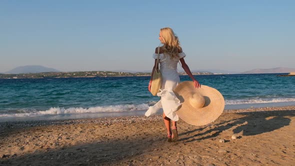 Woman Wearing Straw Hat and White Dress on Shoreline at Spetses Greece