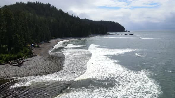 Drone flying along Sombrio beach on Vancouver Island during a slightly cloudy spring morning. Multip