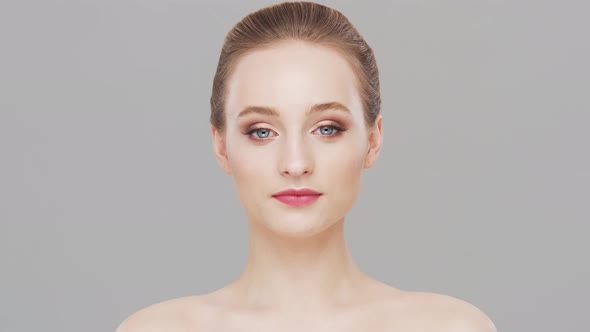 Studio portrait of young, beautiful and natural woman over grey background.