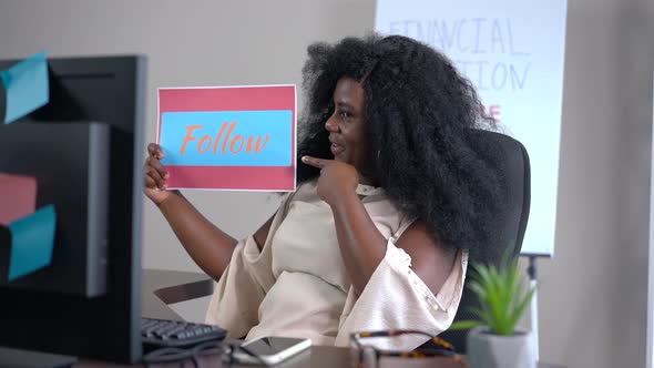 Successful Cheerful African American Blogger Showing Follow Sign Smiling Looking at Monitor